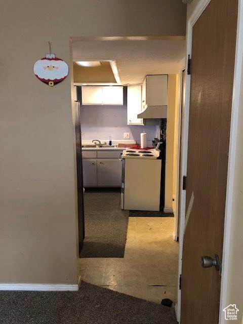 3923 W Rockwood Way Unit G, West Valley City, UT 84120 - kitchen featuring range, carpet flooring, baseboards, a sink, and white cabinetry