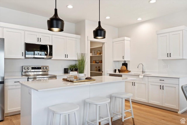 2085 W 1575th Ct S Unit 126, West Haven, UT 84401 - kitchen featuring appliances with stainless steel finishes, a sink, white cabinetry, light countertops, and a kitchen island