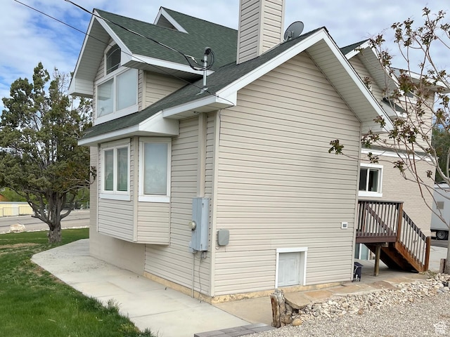 view of home's exterior featuring a chimney and roof with shingles