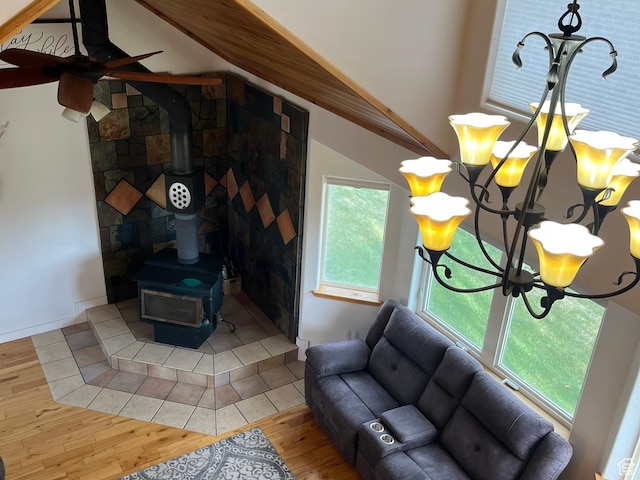 living room with a wood stove, light wood-type flooring, vaulted ceiling, ceiling fan, and a chandelier