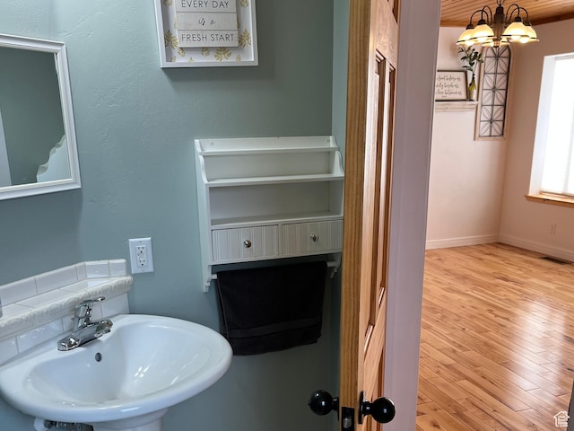 bathroom with a sink, wood finished floors, a chandelier, and baseboards