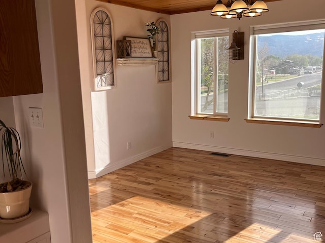 unfurnished dining area with hardwood / wood-style floors, a chandelier, and baseboards