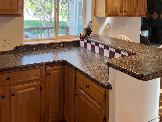 kitchen featuring dark countertops, brown cabinetry, and backsplash