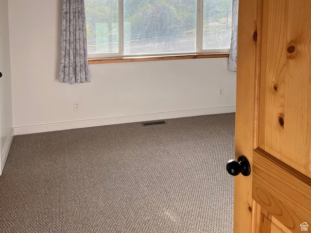 carpeted empty room featuring baseboards