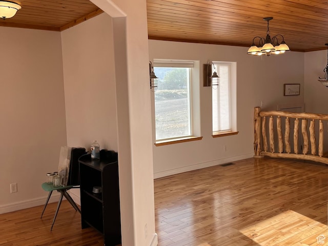 spare room with wood ceiling, wood finished floors, baseboards, a chandelier, and ornamental molding
