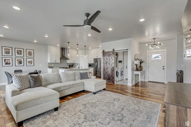 3537 S 5050 W, West Haven, UT 84401 - living room featuring a barn door, washing machine and clothes dryer, ceiling fan, wood finished floors, and baseboards