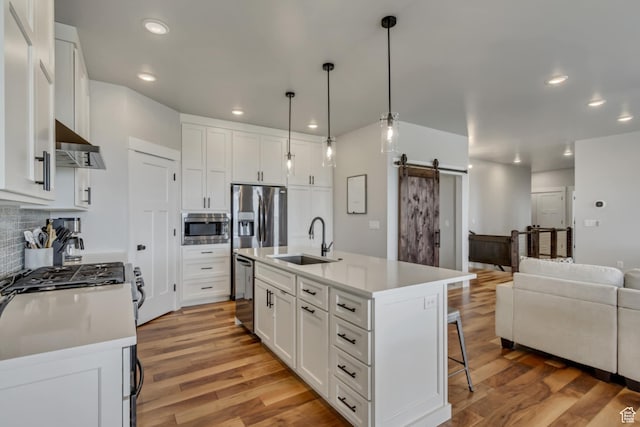 3537 S 5050 W, West Haven, UT 84401 - kitchen featuring a sink, a barn door, stainless steel appliances, wall chimney exhaust hood, and a kitchen breakfast bar