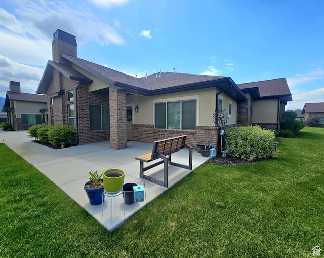 1704 W 300 S Unit Ud/L24, Mapleton, UT 84664 - rear view of house featuring brick siding, a yard, a patio area, a chimney, and stucco siding