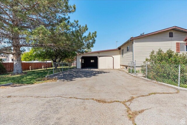 830 E Main St, Grantsville, UT 84029 - view of home's exterior with fence, a detached garage, and asphalt driveway