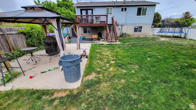 rear view of property with a trampoline, stairs, a wooden deck, a patio area, and a gazebo