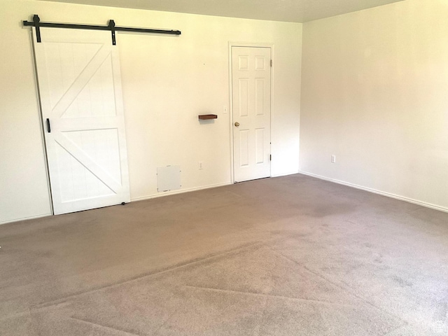 unfurnished bedroom featuring carpet floors, baseboards, and a barn door