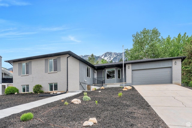 view of front of home featuring brick siding, an attached garage, driveway, and a mountain view