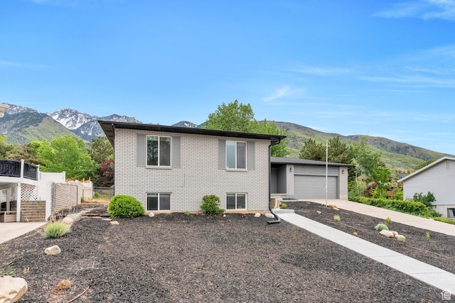 tri-level home featuring a mountain view, brick siding, a garage, and concrete driveway