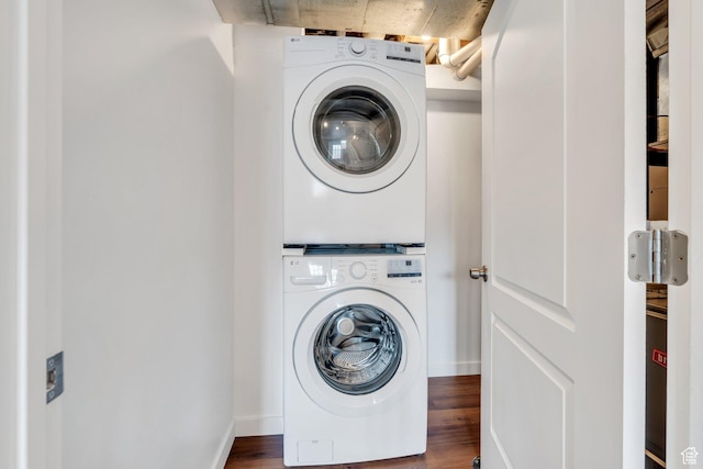 laundry area featuring stacked washer / drying machine, wood finished floors, and baseboards