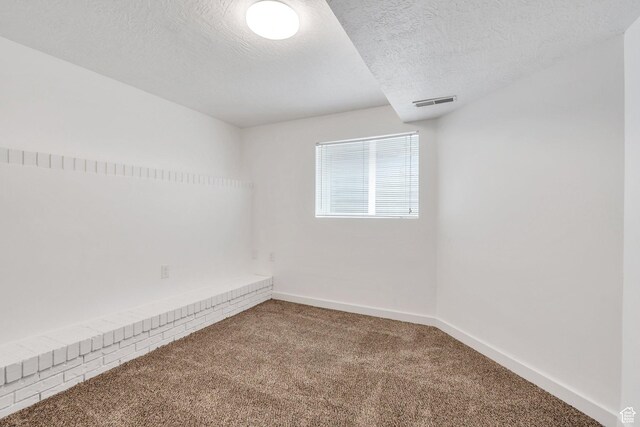 carpeted empty room featuring baseboards and a textured ceiling