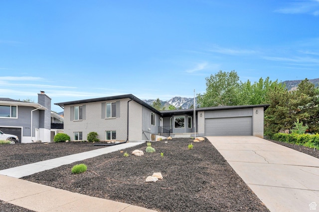 view of front of house with a garage, a mountain view, driveway, and brick siding