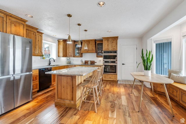 kitchen with black appliances, brown cabinets, light wood finished floors, a kitchen bar, and recessed lighting