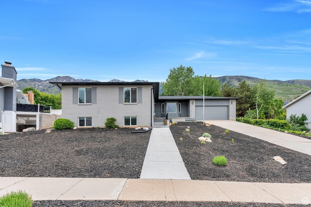 tri-level home with brick siding, a garage, driveway, and a mountain view
