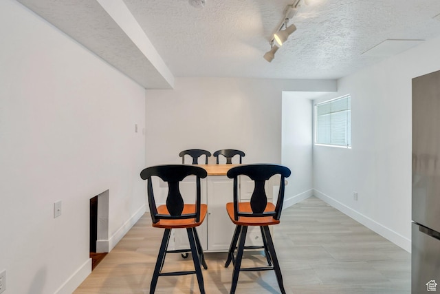 dining space with baseboards, rail lighting, and a textured ceiling
