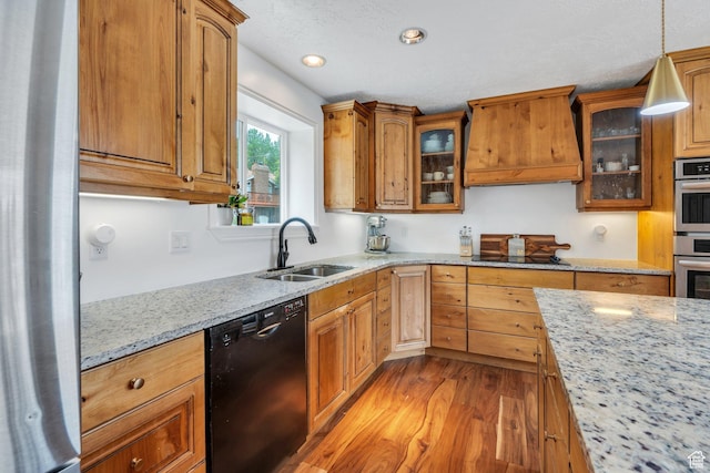 kitchen featuring black appliances, custom exhaust hood, a sink, light wood-style flooring, and light stone countertops