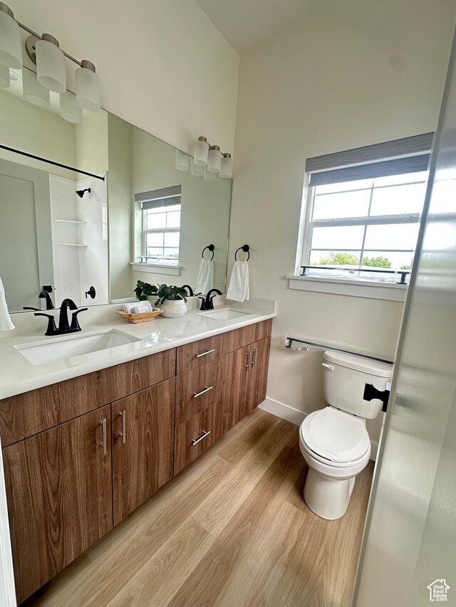 7838 S Holden St, Midvale, UT 84047 - bathroom featuring wood finished floors, toilet, double vanity, and baseboards
