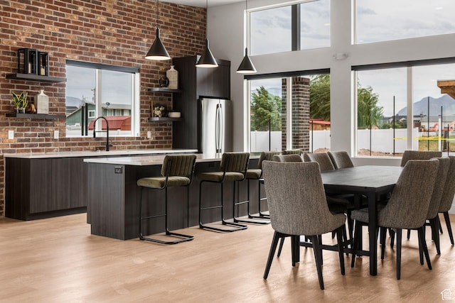 2336 W James Way Unit J34, West Haven, UT 84401 - dining area with light wood finished floors, a mountain view, a towering ceiling, and brick wall