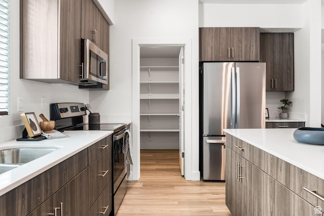 2336 W James Way Unit J34, West Haven, UT 84401 - kitchen featuring appliances with stainless steel finishes, light wood-style flooring, light countertops, modern cabinets, and dark brown cabinets