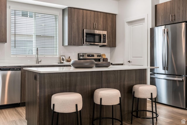 2336 W James Way Unit J34, West Haven, UT 84401 - kitchen featuring stainless steel appliances, a center island, light wood-style flooring, and dark brown cabinets