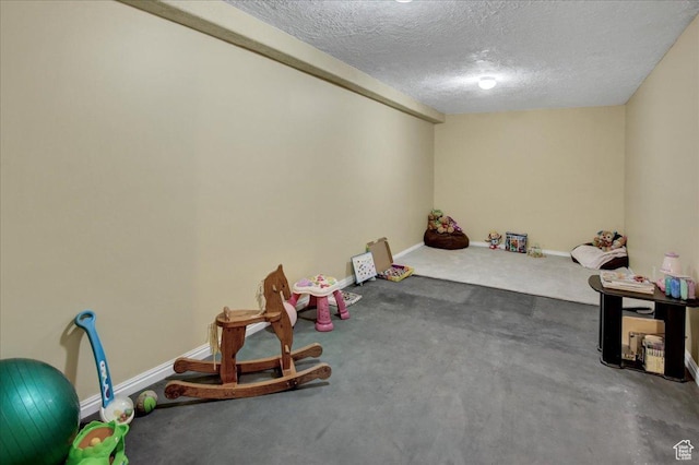 playroom with a textured ceiling, baseboards, and carpet floors