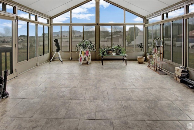 sunroom with healthy amount of natural light, lofted ceiling, and a mountain view