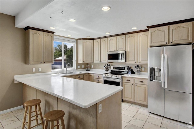 kitchen featuring appliances with stainless steel finishes, a sink, a kitchen bar, recessed lighting, and light countertops