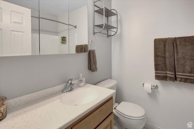 bathroom featuring toilet, vanity, and a shower