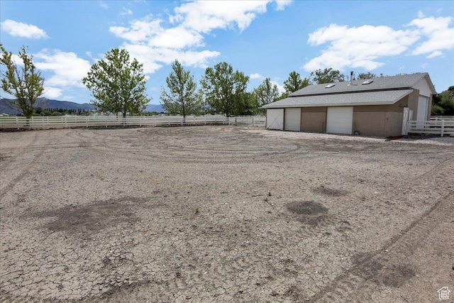 view of yard with a detached garage, fence, a mountain view, and an outdoor structure