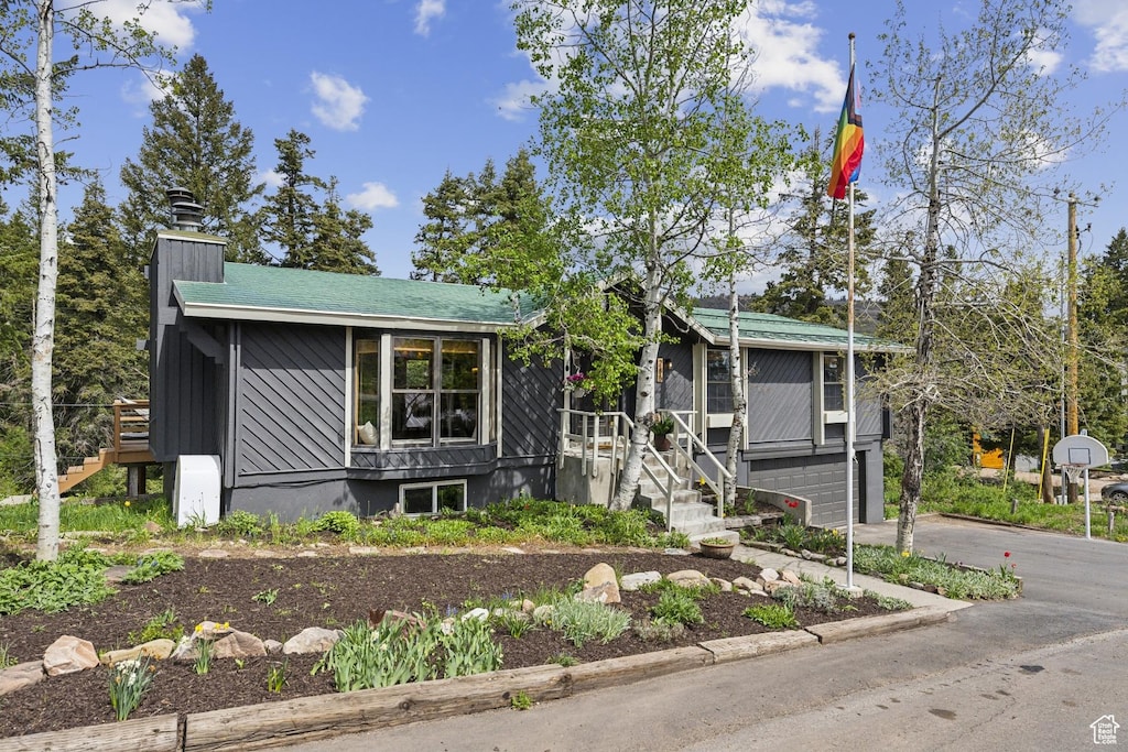 view of front of property with stairway, driveway, a garage, and a chimney