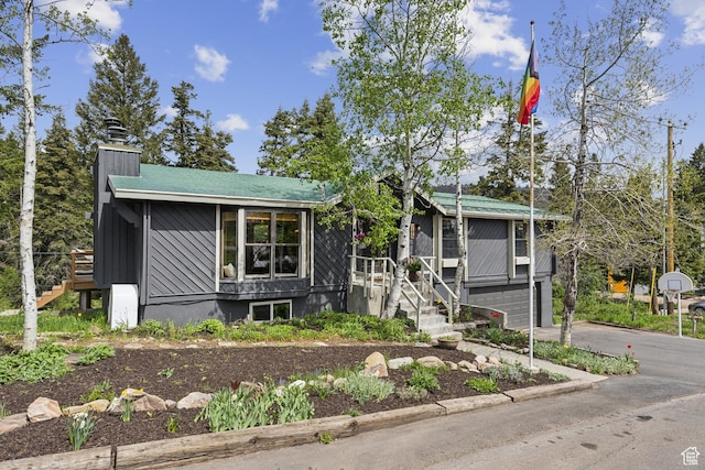view of front of property with stairway, driveway, a garage, and a chimney