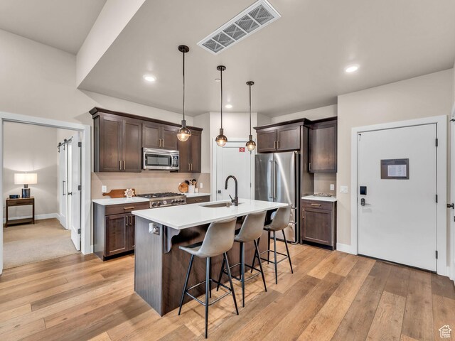 909 W Peace Tree Trl W Unit 416, Heber City, UT 84032 - kitchen featuring appliances with stainless steel finishes, a sink, a breakfast bar, dark brown cabinets, and light countertops