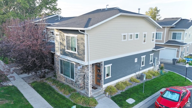 view of side of property with stone siding, a porch, a lawn, and an attached garage