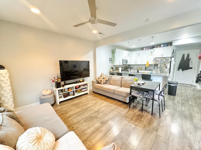 living room with light wood finished floors, a ceiling fan, and recessed lighting