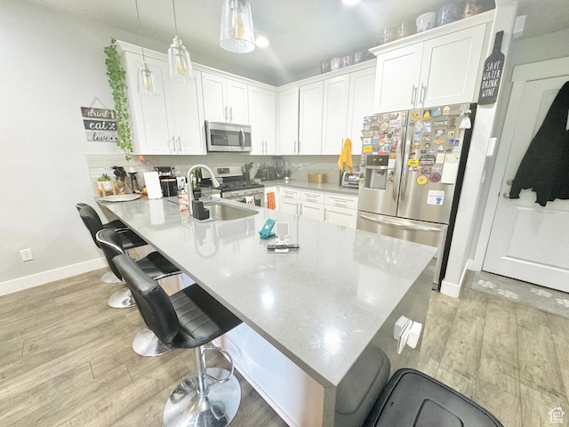kitchen featuring appliances with stainless steel finishes, a breakfast bar area, a peninsula, and white cabinetry