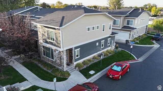 view of home's exterior featuring stone siding, driveway, a garage, and a yard