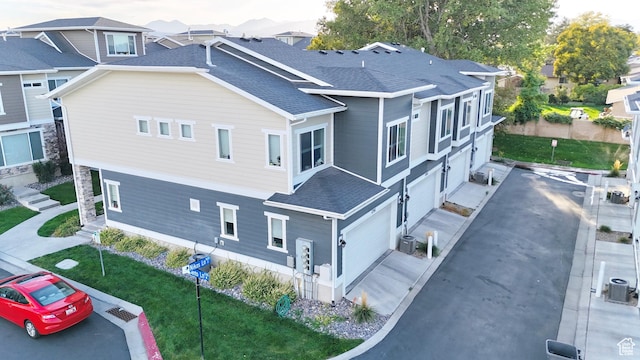 view of property exterior featuring a shingled roof, central air condition unit, an attached garage, and a lawn