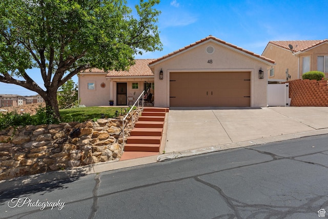 1360 E Telegraph St Unit 48, Washington, UT 84780 - mediterranean / spanish house with concrete driveway, an attached garage, stucco siding, a tile roof, and stairs