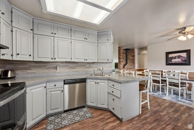kitchen with appliances with stainless steel finishes, a sink, a peninsula, a breakfast bar, and backsplash