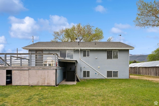 back of house featuring a yard and a shingled roof
