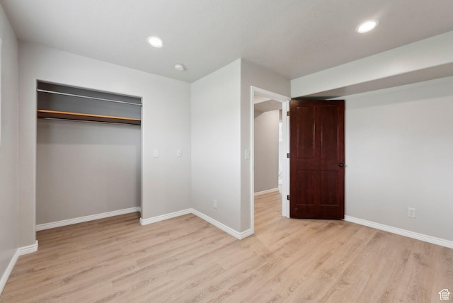 unfurnished bedroom featuring light wood finished floors, baseboards, recessed lighting, and a closet