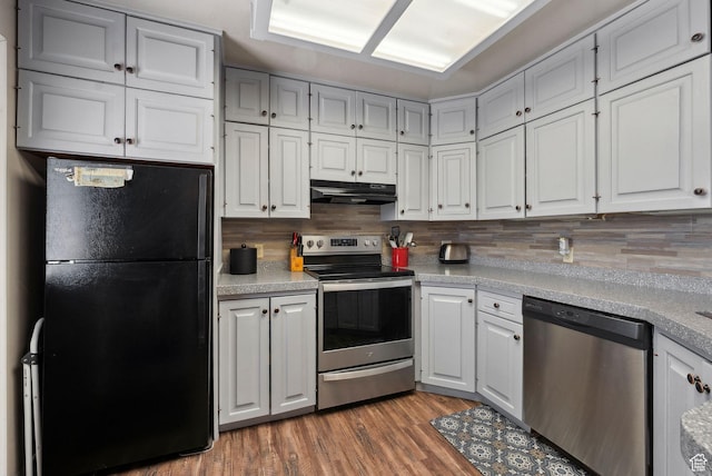 kitchen with stainless steel appliances, under cabinet range hood, tasteful backsplash, light countertops, and light wood-style floors