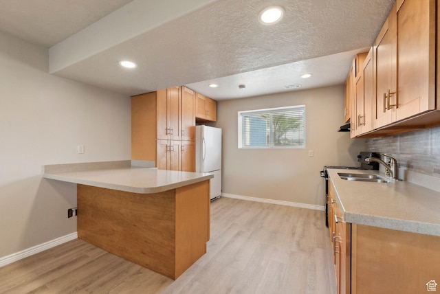kitchen with freestanding refrigerator, light wood-style flooring, baseboards, a peninsula, and light countertops