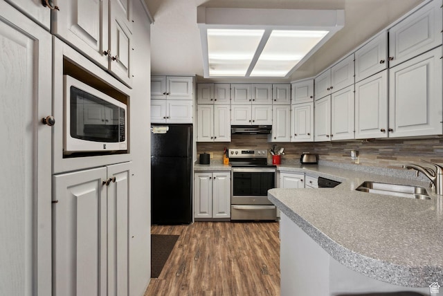 kitchen featuring freestanding refrigerator, stainless steel range with electric cooktop, under cabinet range hood, a sink, and backsplash