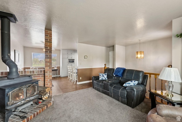 carpeted living room with a wood stove, a chandelier, baseboards, and wood finished floors