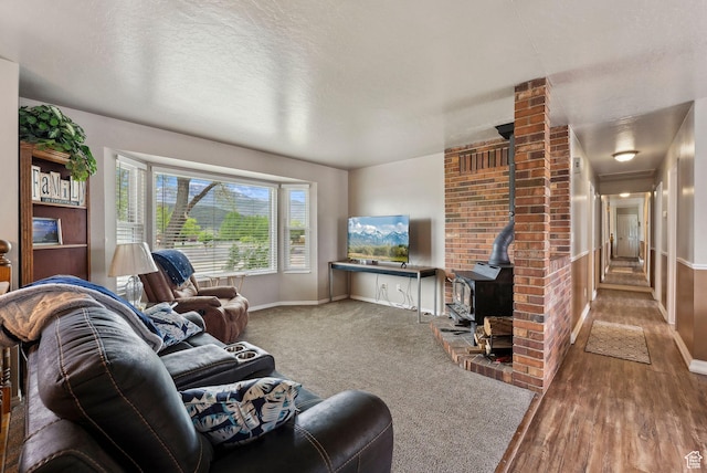 living room featuring a wood stove, baseboards, wood finished floors, and a textured ceiling